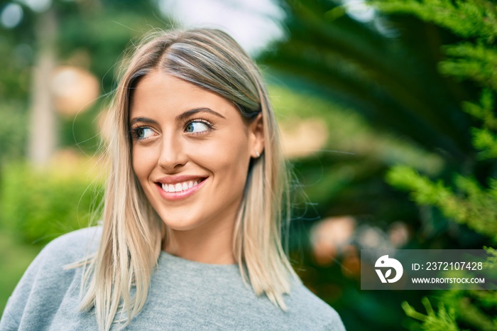 Young blonde girl smiling happy standing at the park.