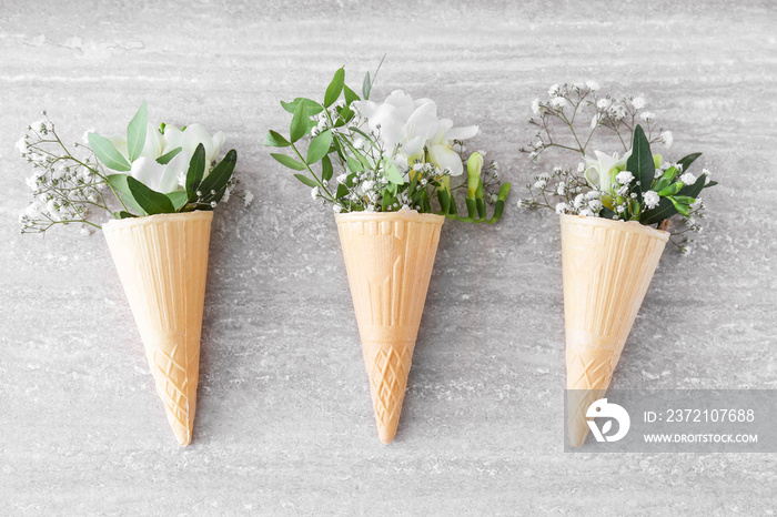 Wafer cones with beautiful freesia flowers on grey background