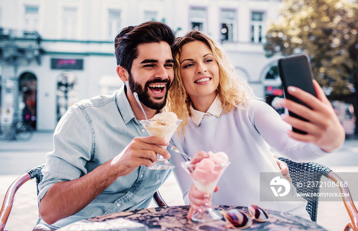 Dating in the cafe. Loving couple eating ice cream and taking a selfie with a mobile phone. Love and