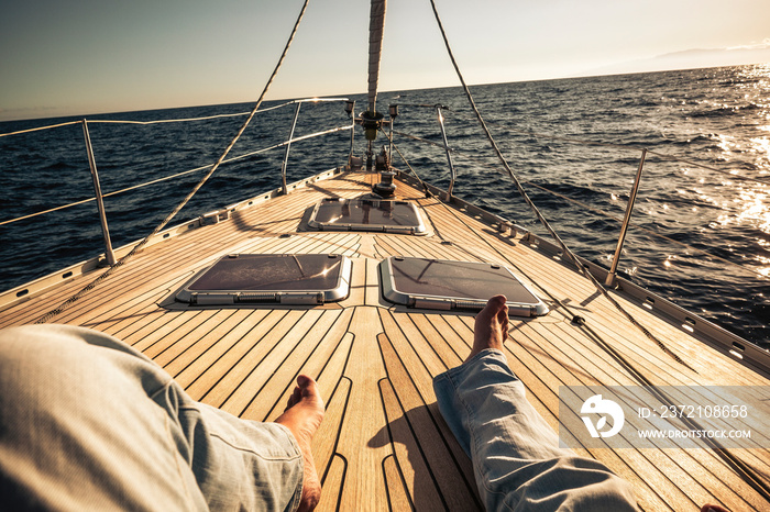 男人躺在一艘美丽的木帆船上享受旅行的腿的视角