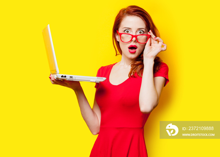 photo of beautiful young woman holding laptop on the wonderful yellow studio background