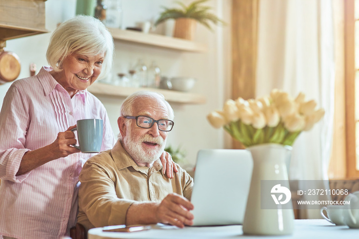 Happy elderly couple is having breakfast at home