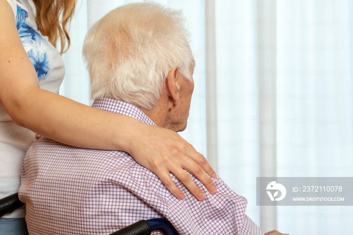 Rear view of old man with female hand on shoulder.