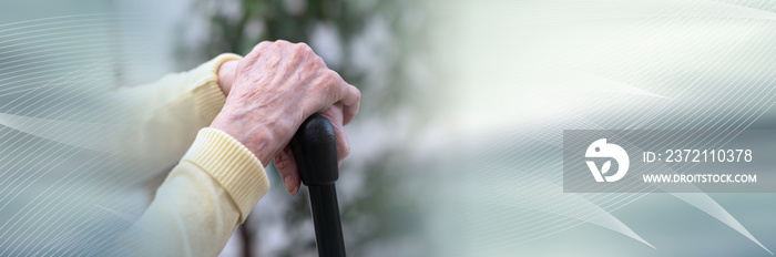 Old woman hands holding a cane; panoramic banner