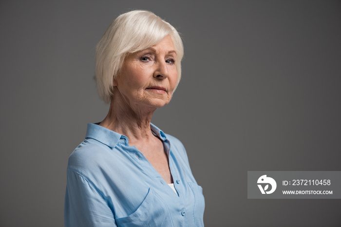 portrait of serious senior woman isolated on grey in studio