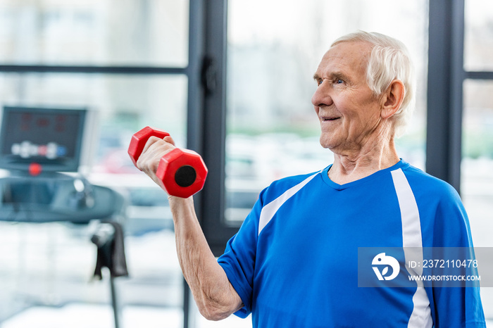 happy senior sportsman exercising with dumbbell at gym