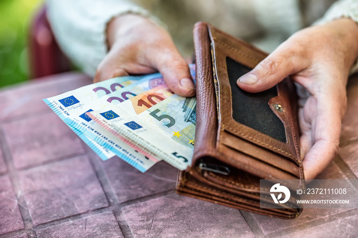 Pensioner woman holding in hands wallet with money.