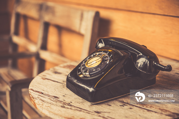 木桌上的老式电话黑色。经典复古风格的旋转拨号呼叫电话t