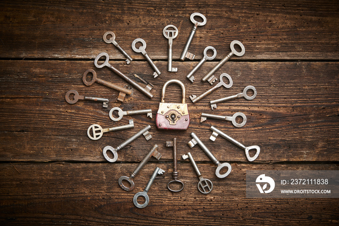 Vintage rusty padlock surrounded by old keys on a weathered steel background