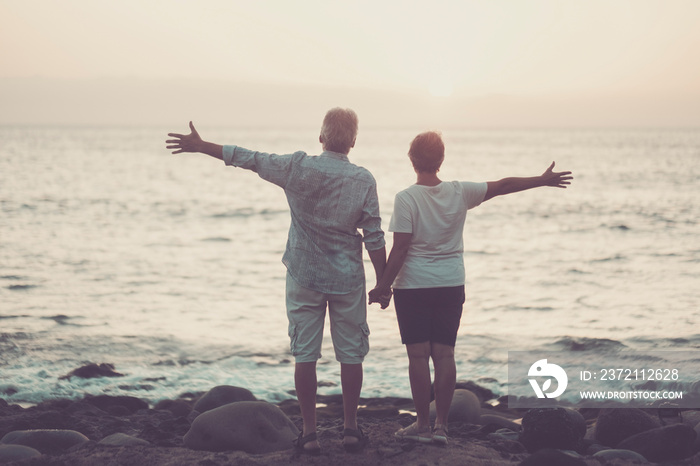 Valentines day love couple concept with senior aged people open arms with ocean and sunset in front