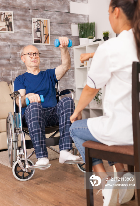 坐在轮椅上的爷爷在护士的帮助下做运动。有社交能力的残疾老人