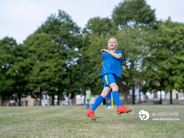 女孩（8-9岁）穿着制服在足球场上练习