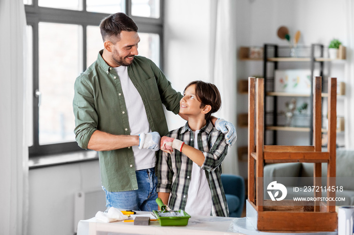 family, diy and home improvement concept - happy smiling father and son in gloves restoring old tabl