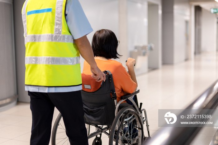 Caretaker push elderly woman on wheelchair in airport terminal.