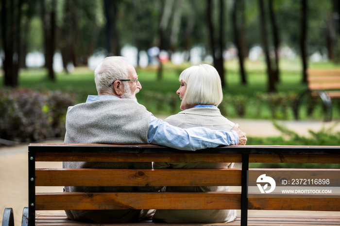 幸福的老年夫妇在公园的木长椅上休息