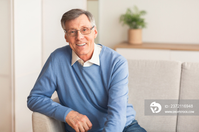 Elderly Gentleman Smiling Sitting On Sofa At Home