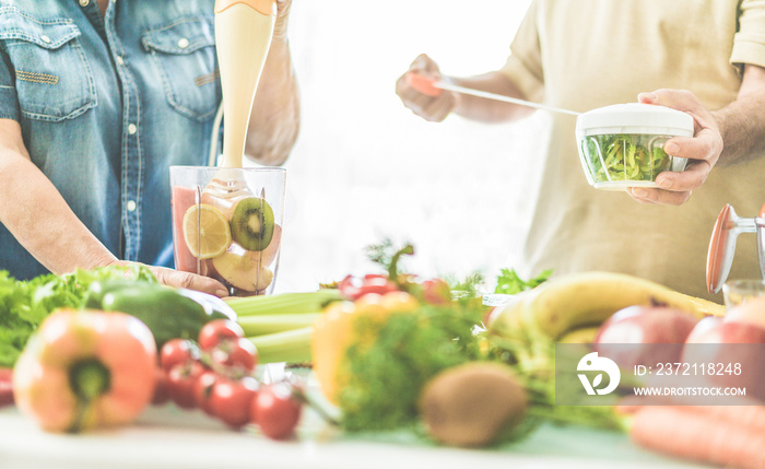 Senior couple preparing vegan smoothie with bio fruits and vegatables - Old people having vegetarian