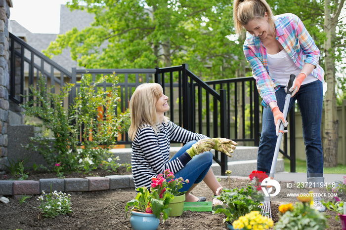 mature mother and daughter working on flower garden