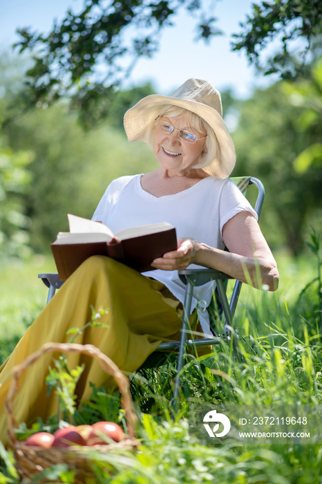 微笑的老妇人在花园里看书