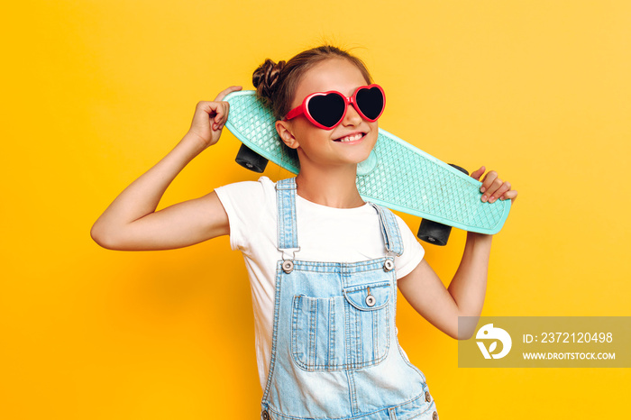 Happy teenager with skateboard, stylish girl posing on yellow background