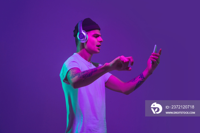 Listen to music with smartphone, dancing. Caucasian mans portrait isolated on purple studio backgro