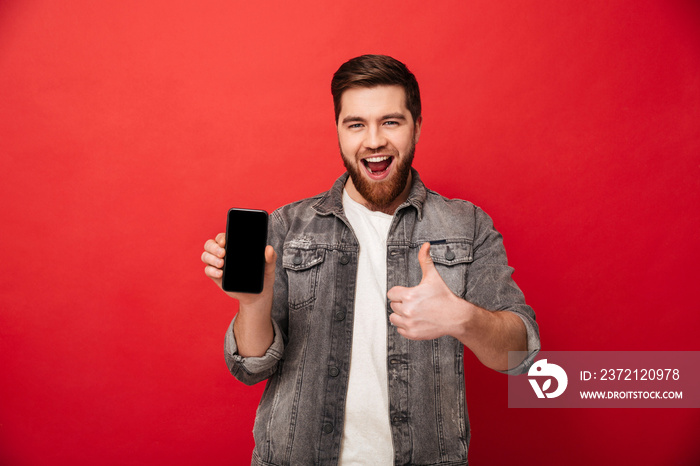 一个没有胡子的快乐男人在镜头前展示手机，竖起大拇指，被红色b隔离的画面