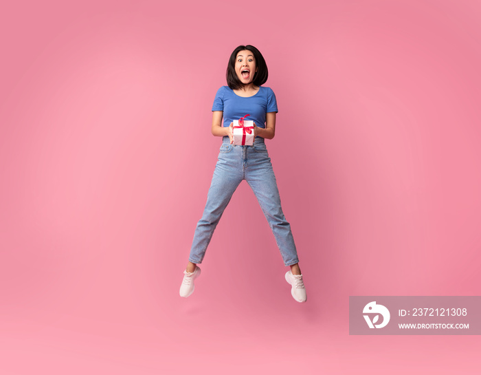 Jumping excited asian lady holding present box