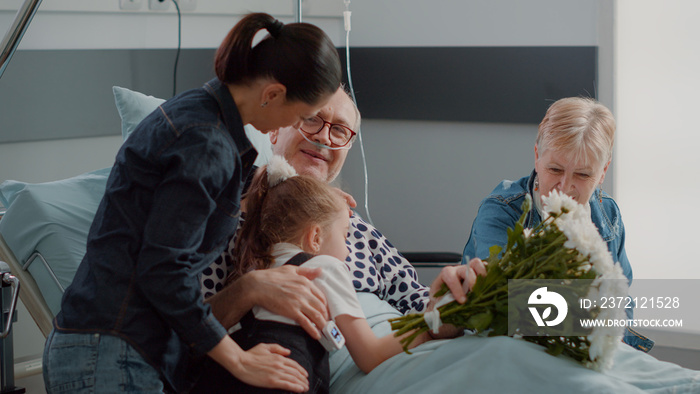 母亲和孩子在医院病房看望爷爷，给老人送花的特写