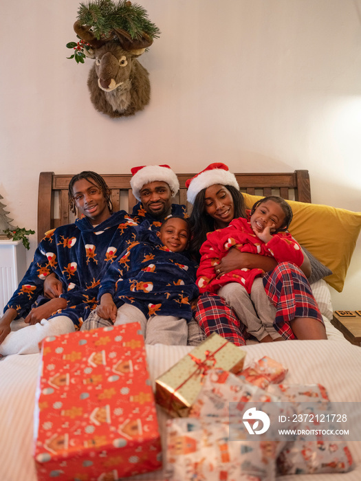 Family portrait with Christmas presents in bed at home