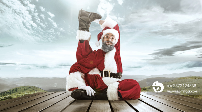 Santa Claus in traditional red white costume in front of white snow winter landscape panorama. Chris