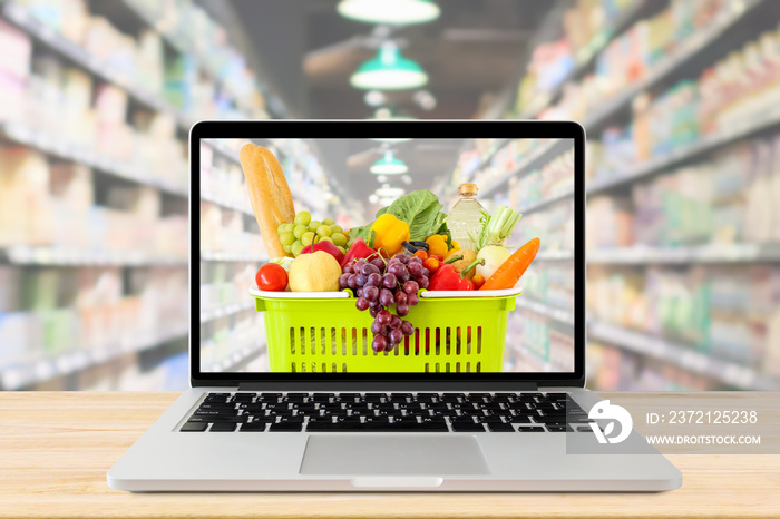 supermarket aisle blurred background with laptop computer and shopping basket on wood table grocery 