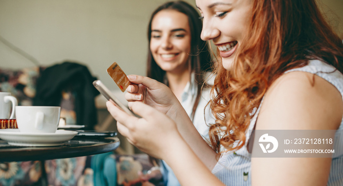 Portrait of a charming plus size women using a smartphone and a gold credit card smiling while sitti