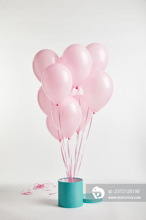 bundle of pink festive air balloons with turquoise gift box on white