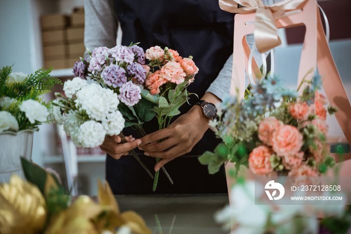 portrait florist preparing a gift flower on table workspace for customer