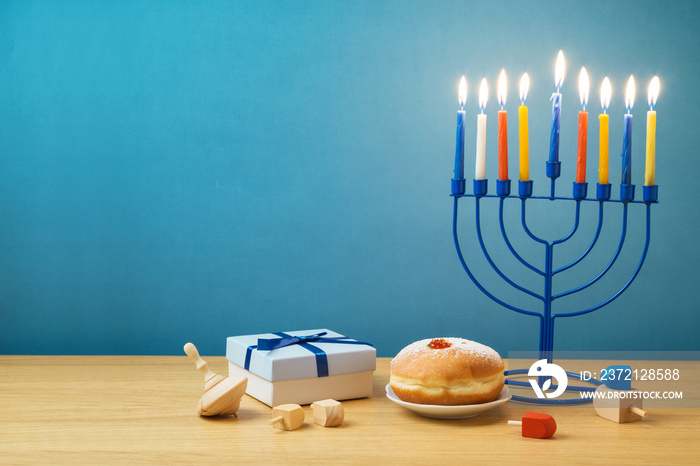 Jewish holiday Hanukkah background with menorah, sufganiyot, gift box and spinning top on wooden tab