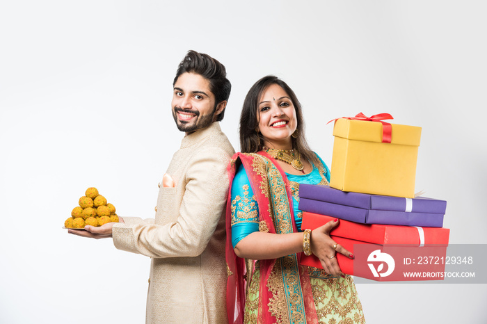 Indian couple with laddu and gift boxes on diwali /festival, standing isolated over white background