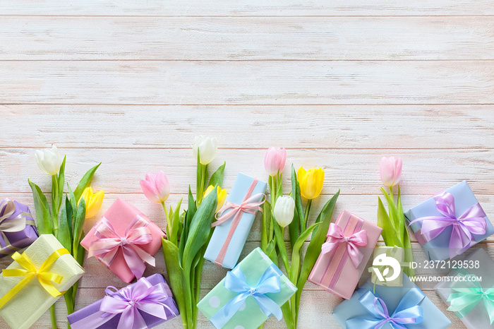 Composition with gift boxes and flowers for International Womens Day celebration on light wooden ba