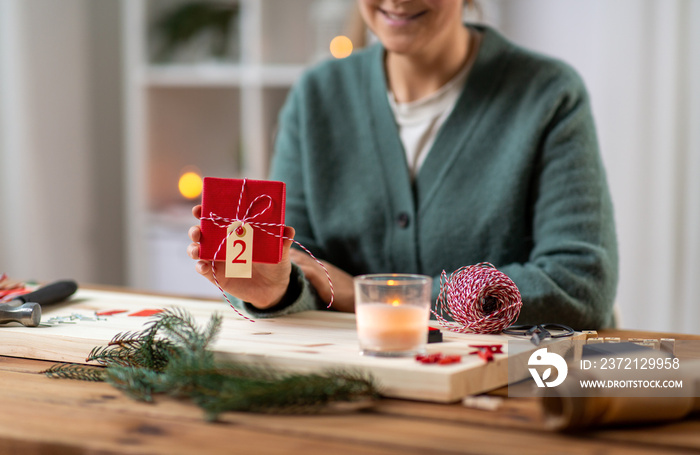 winter holidays and hobby concept - close up of woman showing packed christmas gift for advent calen