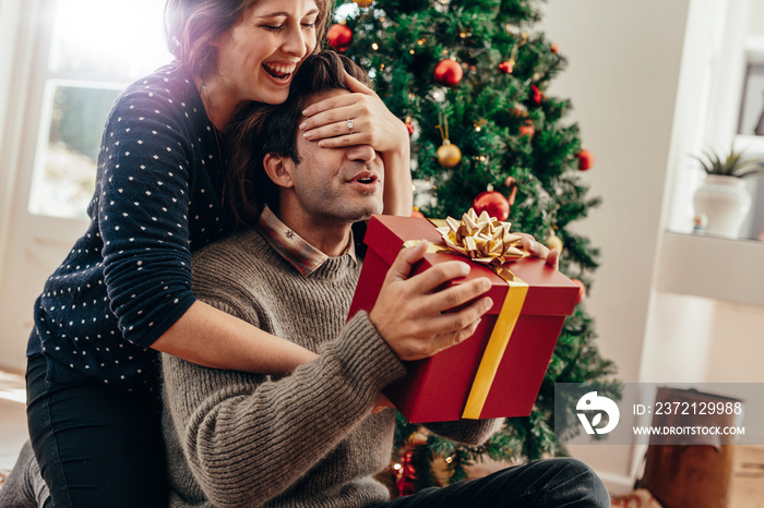 Young couple having fun celebrating Christmas with gifts.