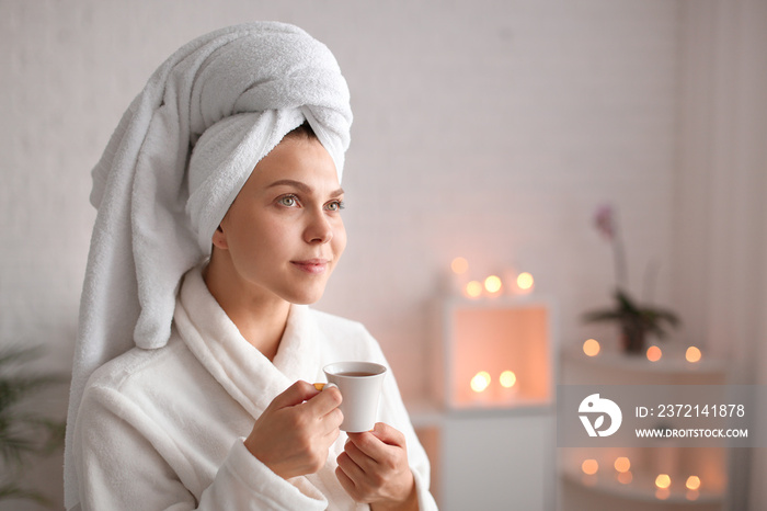 Beautiful young woman with cup of tea relaxing in spa salon