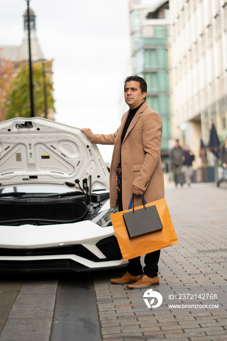 Man with shopping bags standing by luxury car