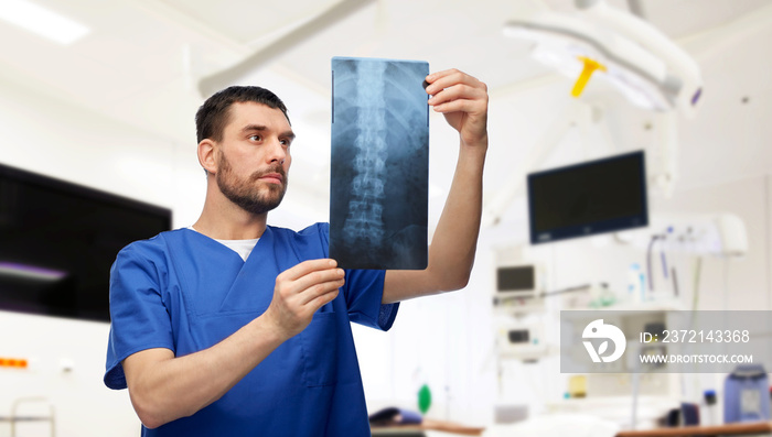医学、医疗保健和外科概念-穿着蓝色制服的医生或男护士在看x光片