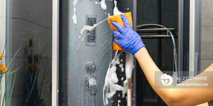 Cleaning of shower steam cabins from calcium deposits. Cleaning in the bathroom. hand in gloves with