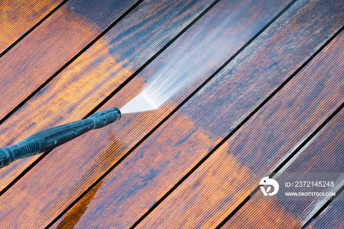 cleaning terrace with a power washer - high water pressure cleaner on wooden terrace surface