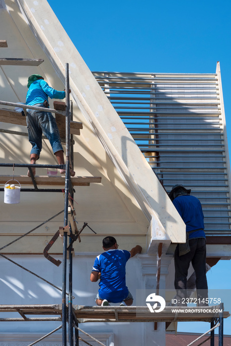 Asian builder workers with work tools on scaffolding are working to renovate external roof structure