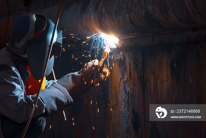 Welder with safety equipment using arc welding machine to welding hull surface of the old vessel in 