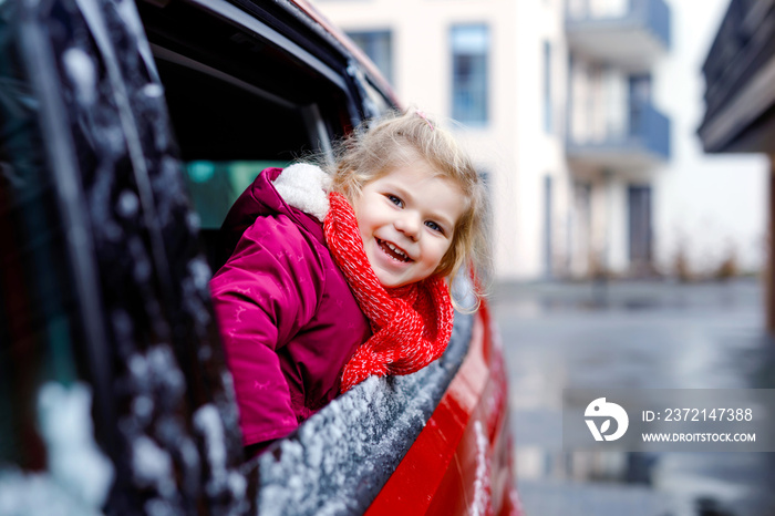 Cute adorable happy toddler girl sitting in car before leaving for winter vacations with parents. Li