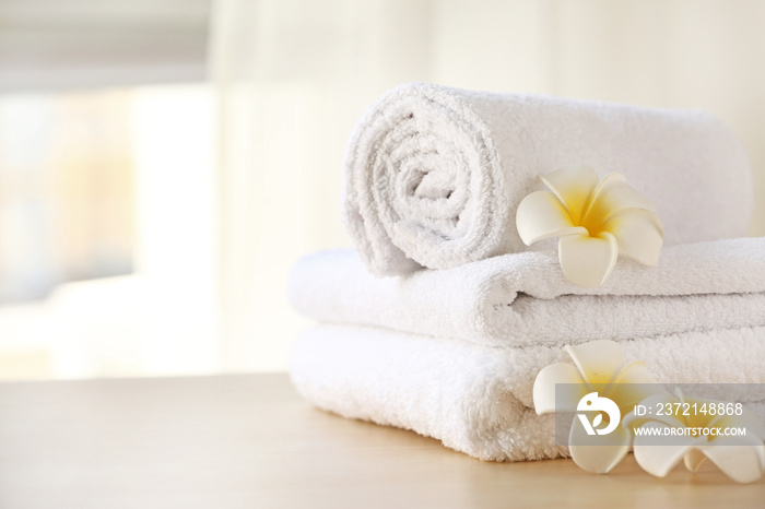 Clean towels with flowers on table in room