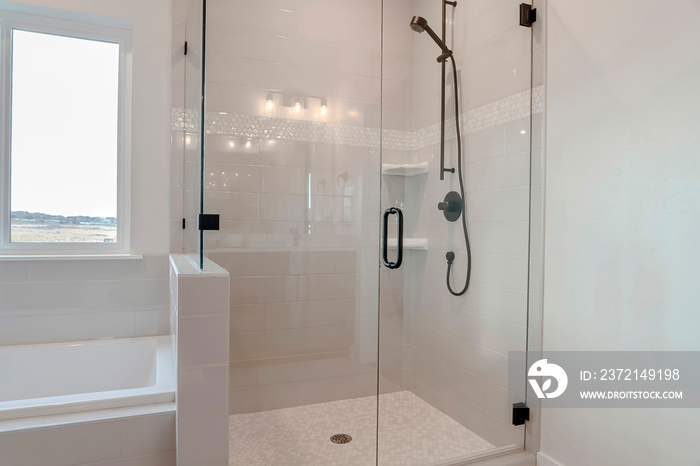 Bathroom shower stall with half glass enclosure adjacent to built in bathtub