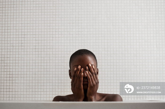 Young woman covering her face in bathroom